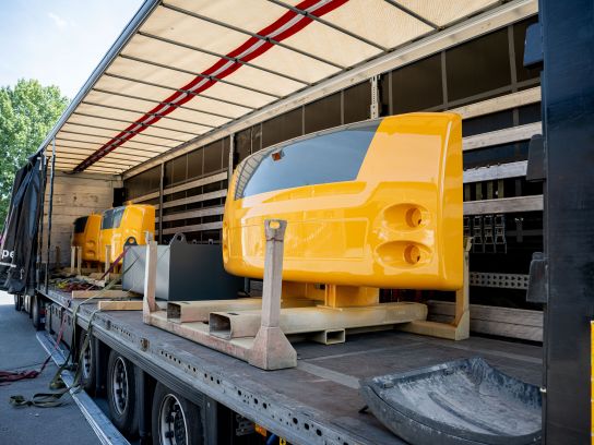 Blick auf die geöffnete Ladefläche eines LKWs der mit gelben Gehäuseteilen und Gegengewichten beladen ist. Die Aufnahme verdeutlicht die professionelle Ladungssicherung und die Abwicklung der kompletten Exportlogistik für internationale Kunden.